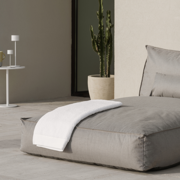 Cozy outdoor seating area with a gray cushion and a white towel beside a potted cactus.