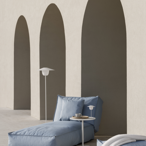 Moderner Außen-Loungebereich mit blauen Kissen und minimalistischer Dekoration unter gewölbter Architektur.