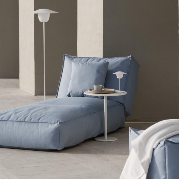 Cozy blue lounge chair with a small side table and a cup in a modern interior setting.