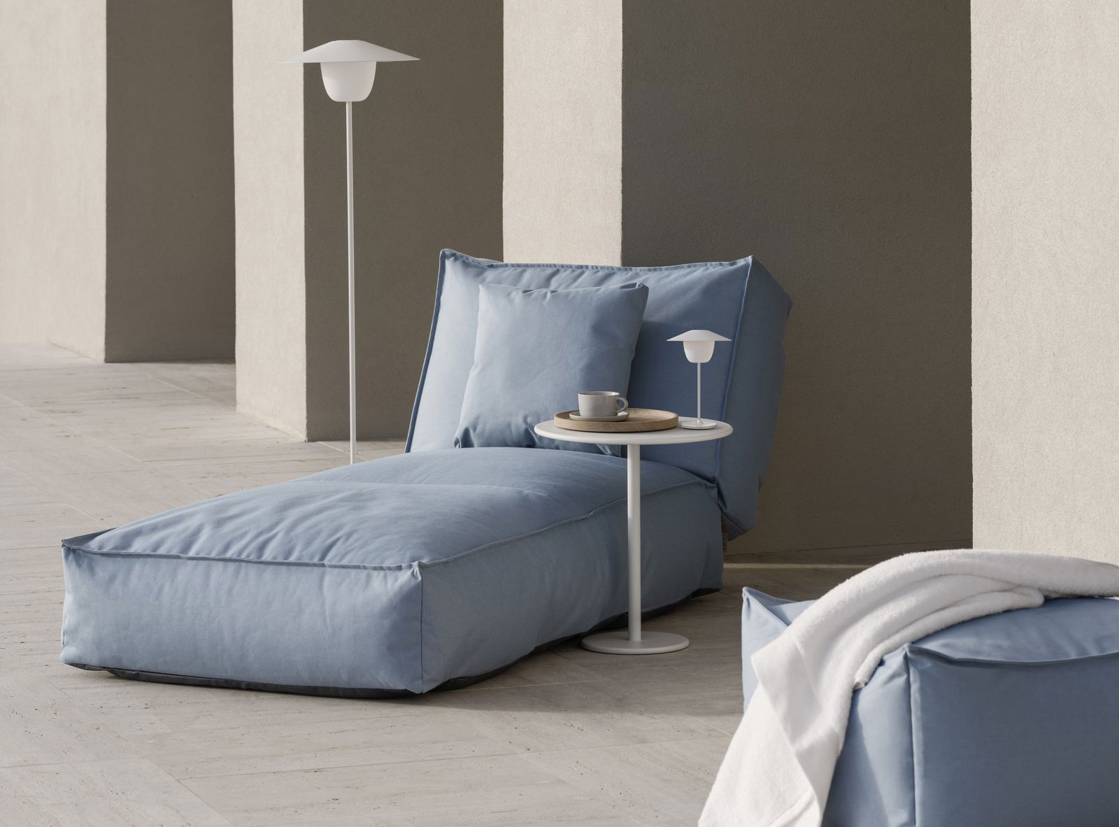 Cozy blue lounge chair with a small side table and a cup in a modern interior setting.