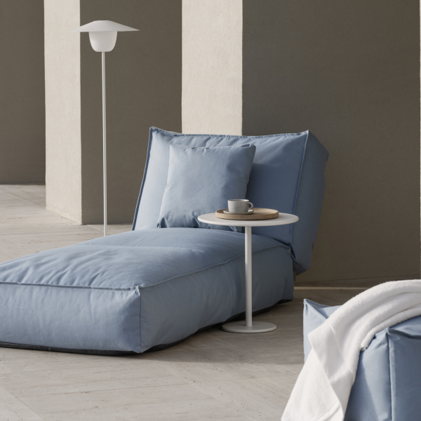 Cozy blue lounge chair with a side table and a coffee cup in a modern interior setting.