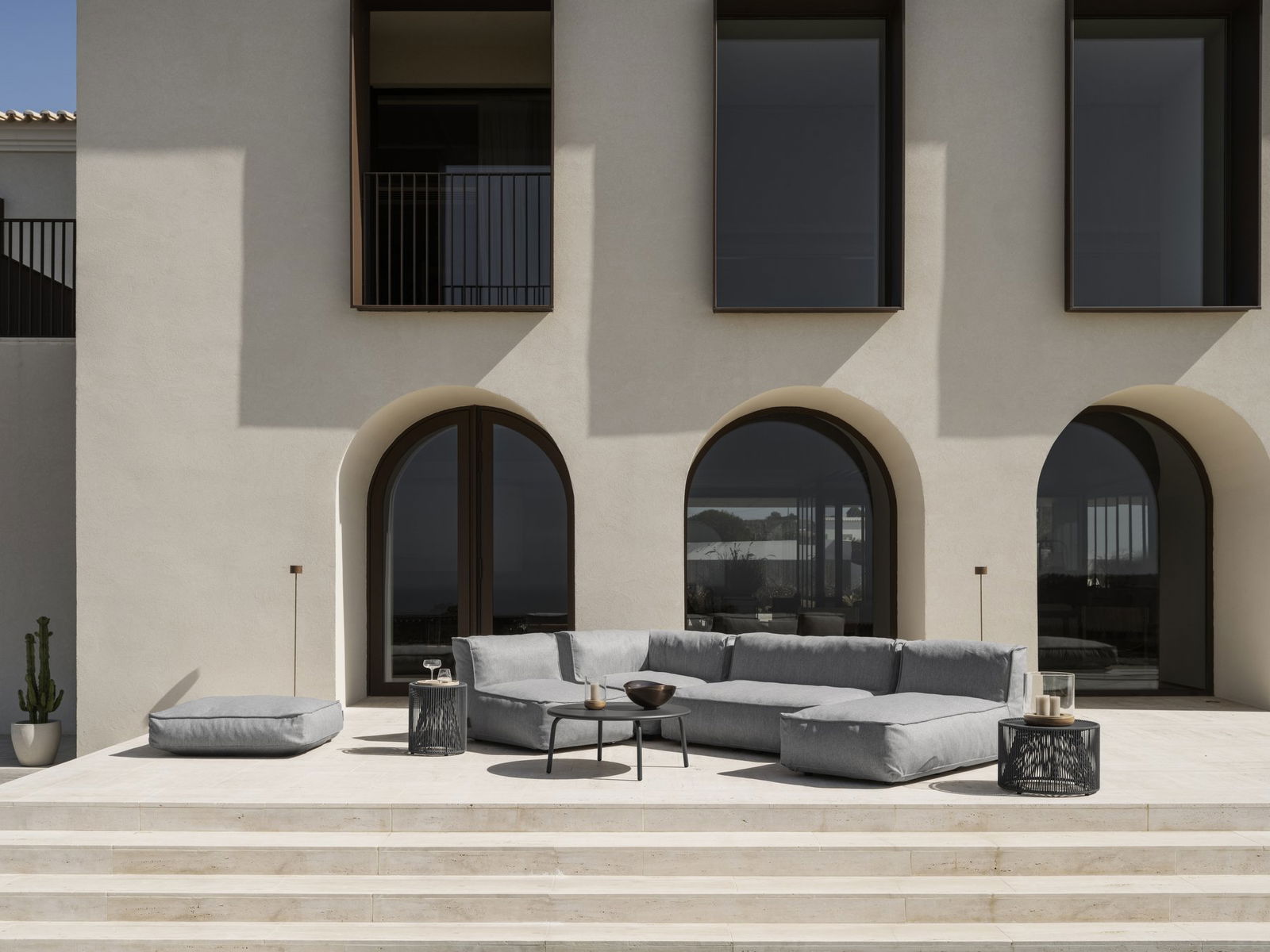 Eleganter Außenloungebereich mit modernen Möbeln und Bogenfenstern, die einen malerischen Blick bieten.