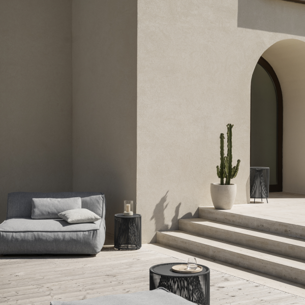 Moderner Outdoor-Patio mit einem minimalistischen Sofa, stilvollen Tischen und einem großen Kaktus.