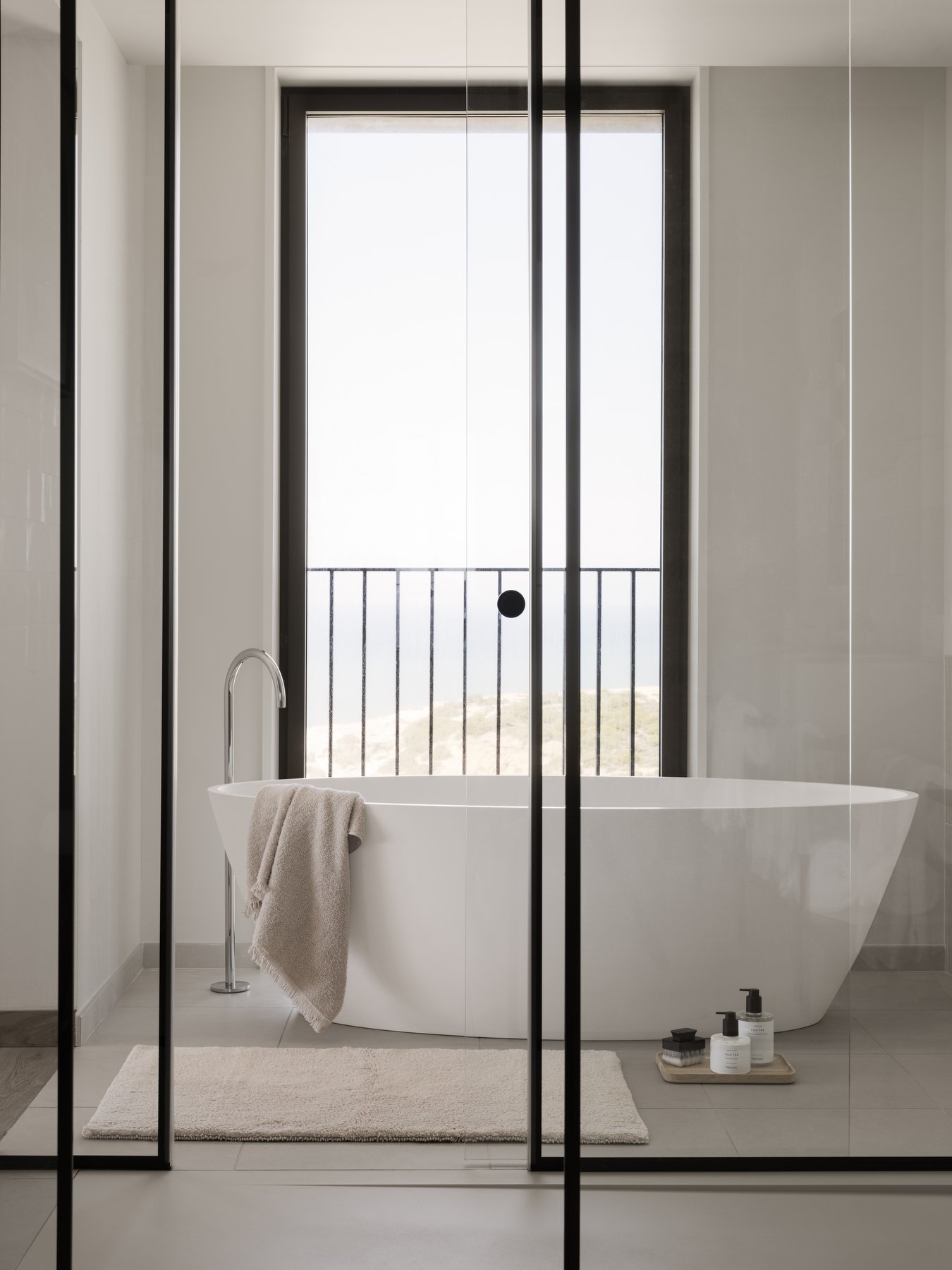 Modernes Badezimmer mit freistehender Badewanne und einer malerischen Aussicht durch große Fenster.