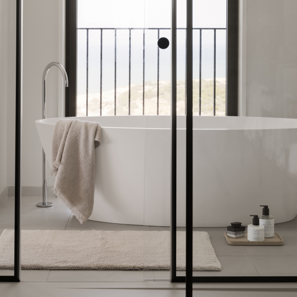 Modernes Badezimmer mit einer freistehenden Badewanne und Meerblick, ausgestattet mit minimalistischer Dekoration.