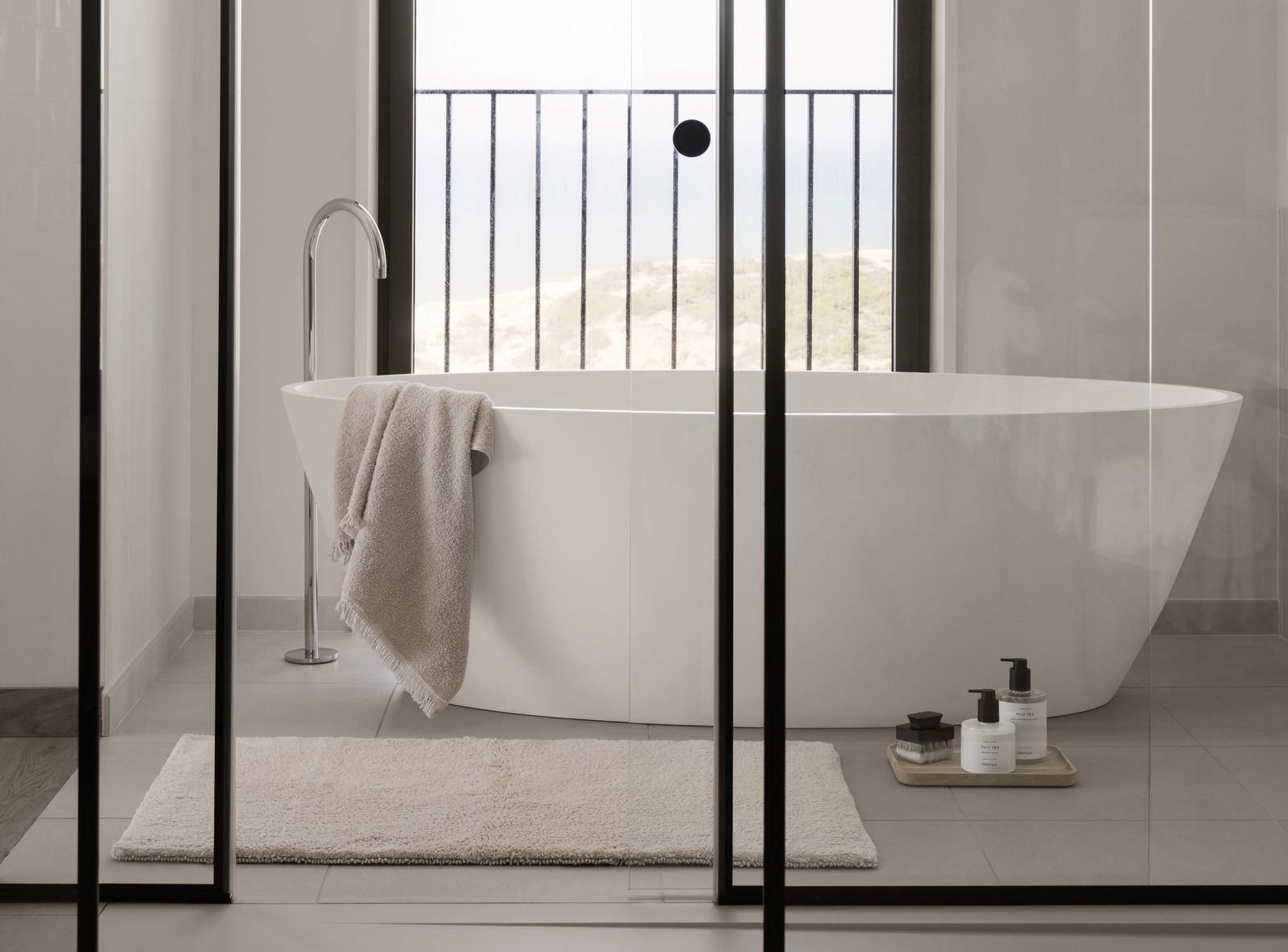 Modernes Badezimmer mit einer freistehenden Badewanne und Meerblick, ausgestattet mit minimalistischer Dekoration.