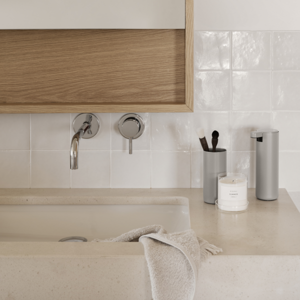 Moderner Badezimmerwaschtisch mit eleganten Armaturen, dekorativen Accessoires und sanften neutralen Farben.
