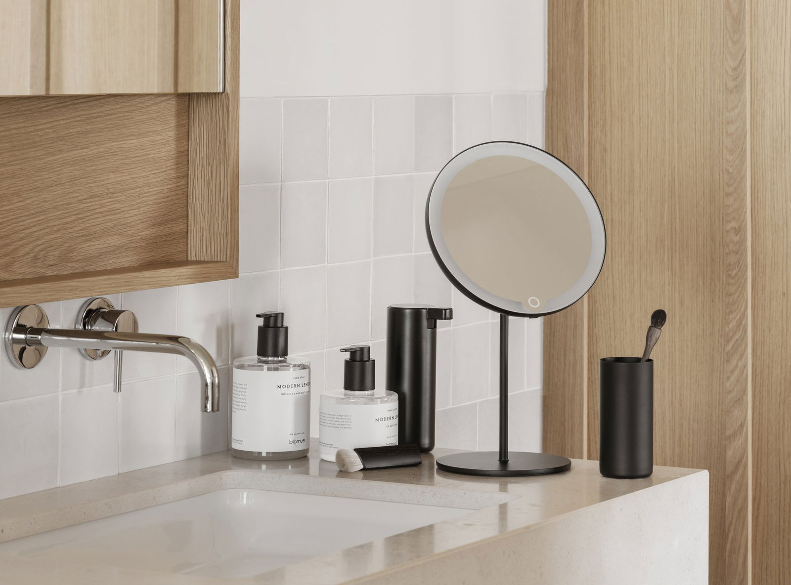 Modernes Badezimmer-Waschtisch mit Spiegel, eleganten Spendern und minimalistischer Dekoration.