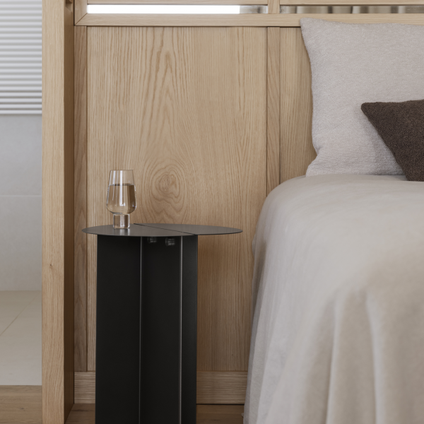 Modernes Schlafzimmer mit einem minimalistischen Nachttisch und einem Glas Wasser neben einem gemütlichen Bett.