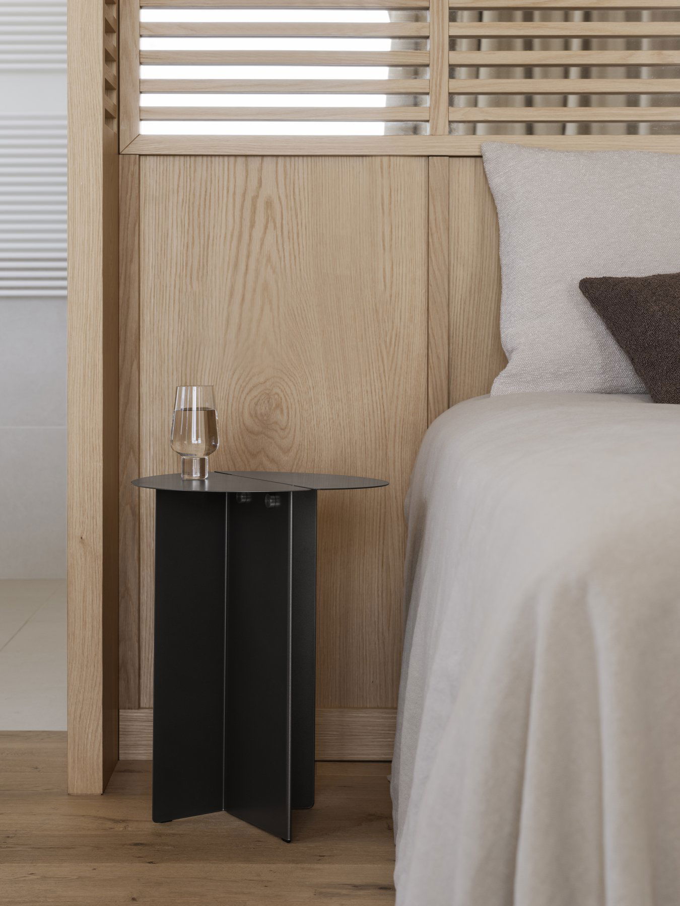 Modernes Schlafzimmer mit einem minimalistischen Nachttisch und einem Glas Wasser neben einem gemütlichen Bett.