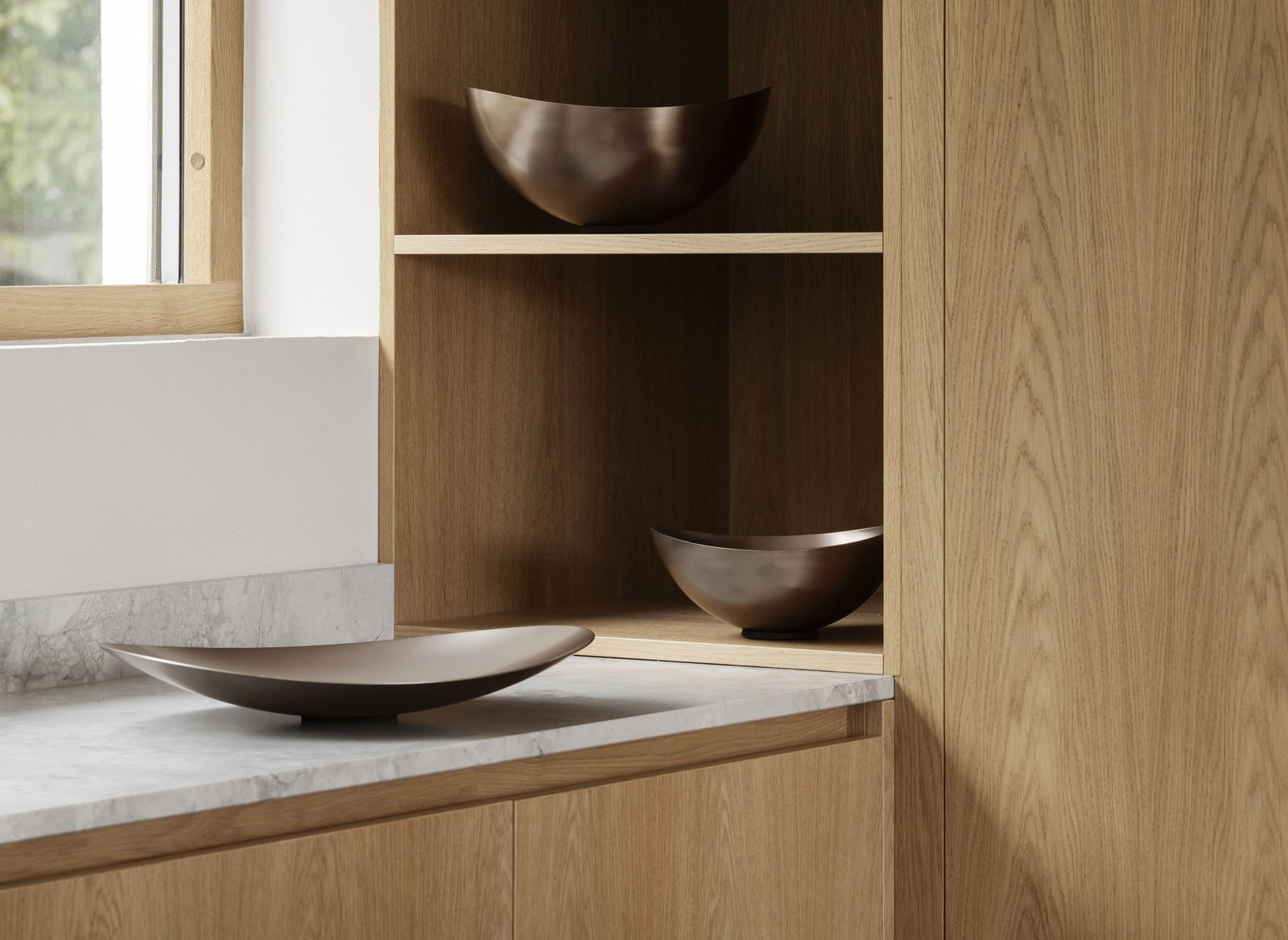 Elegante Holzschränke mit stilvollen Metalltellern, die in einer modernen Küchenumgebung ausgestellt sind.