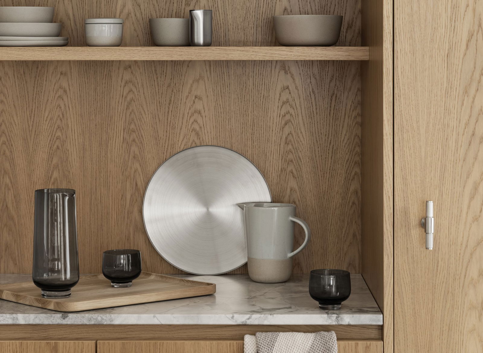 Sleek kitchen display featuring modern tableware and minimalist decor on wooden shelves.