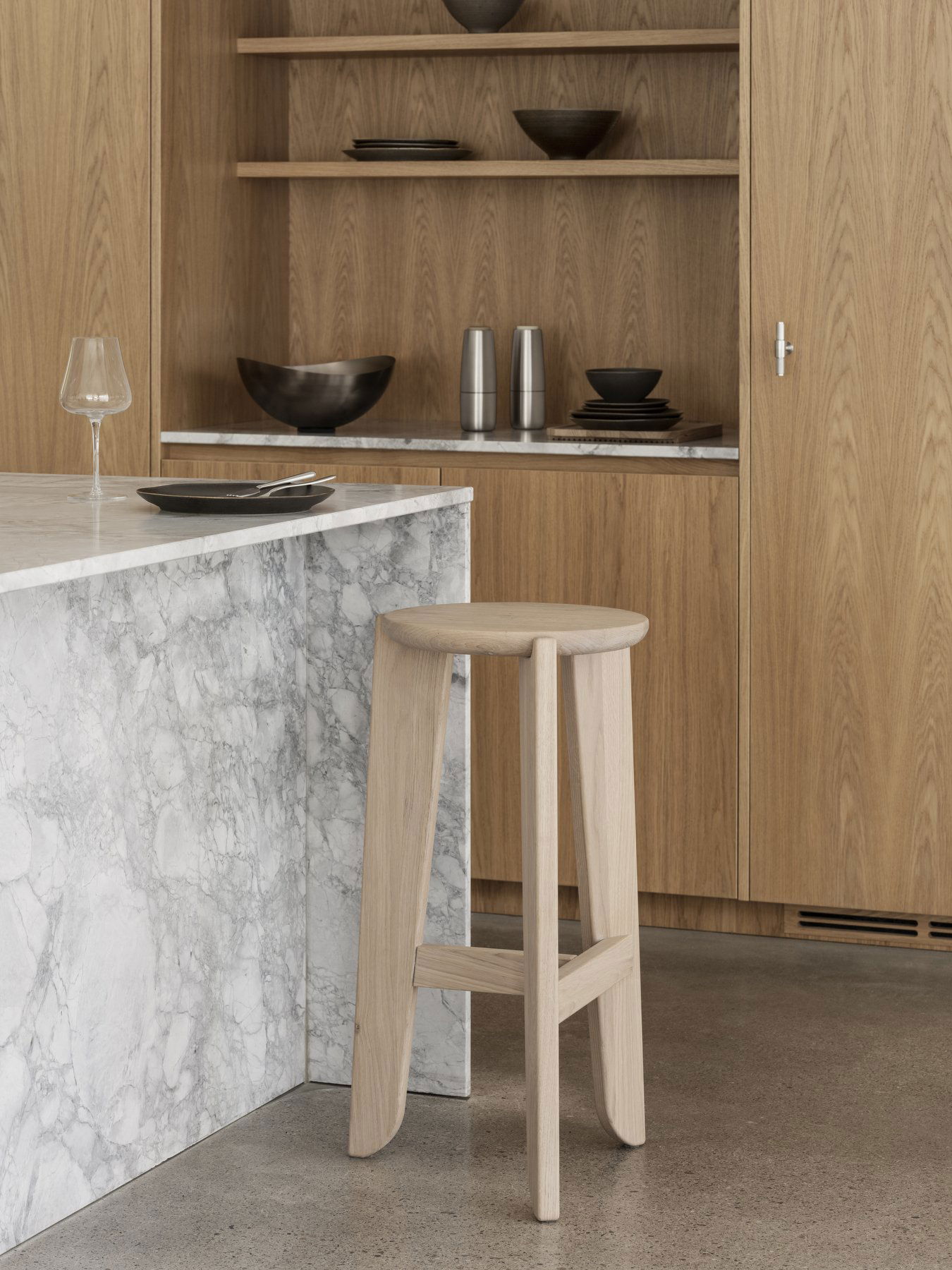 Moderne Küche mit Holzschränken, Marmorarbeitsplatte und einfachem Hockerdesign.