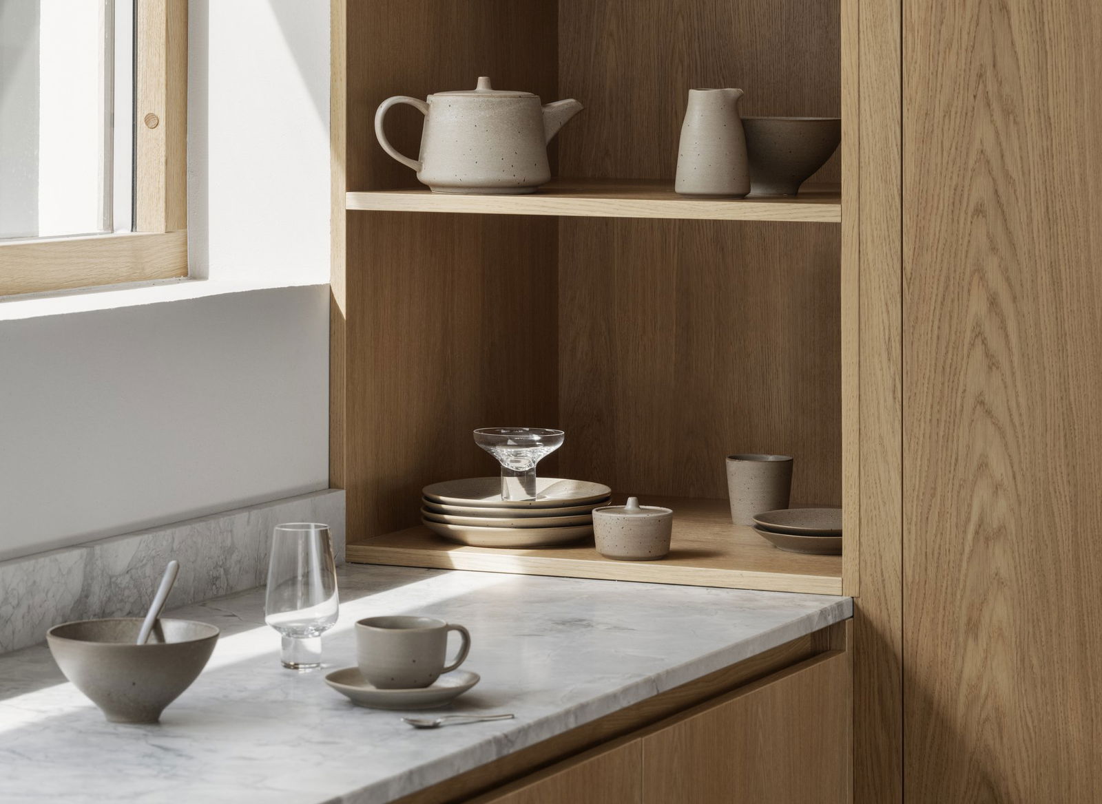 Moderne Küchenschränke, die minimalistische Keramikteller und Glaswaren präsentieren.