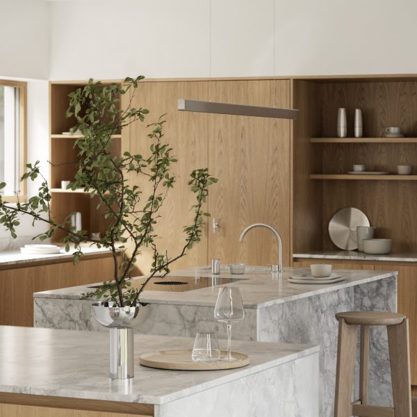 Moderne Küche mit Marmorinsel, Holzmöbeln und einer minimalistischen dekorativen Pflanze.
