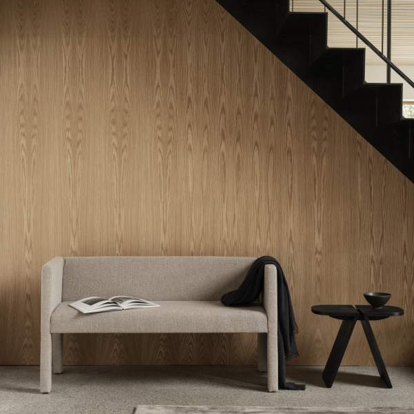Gemütlicher Wohnraum mit einem minimalistischen Sofa und einem modernen Beistelltisch vor einer Holzwand.