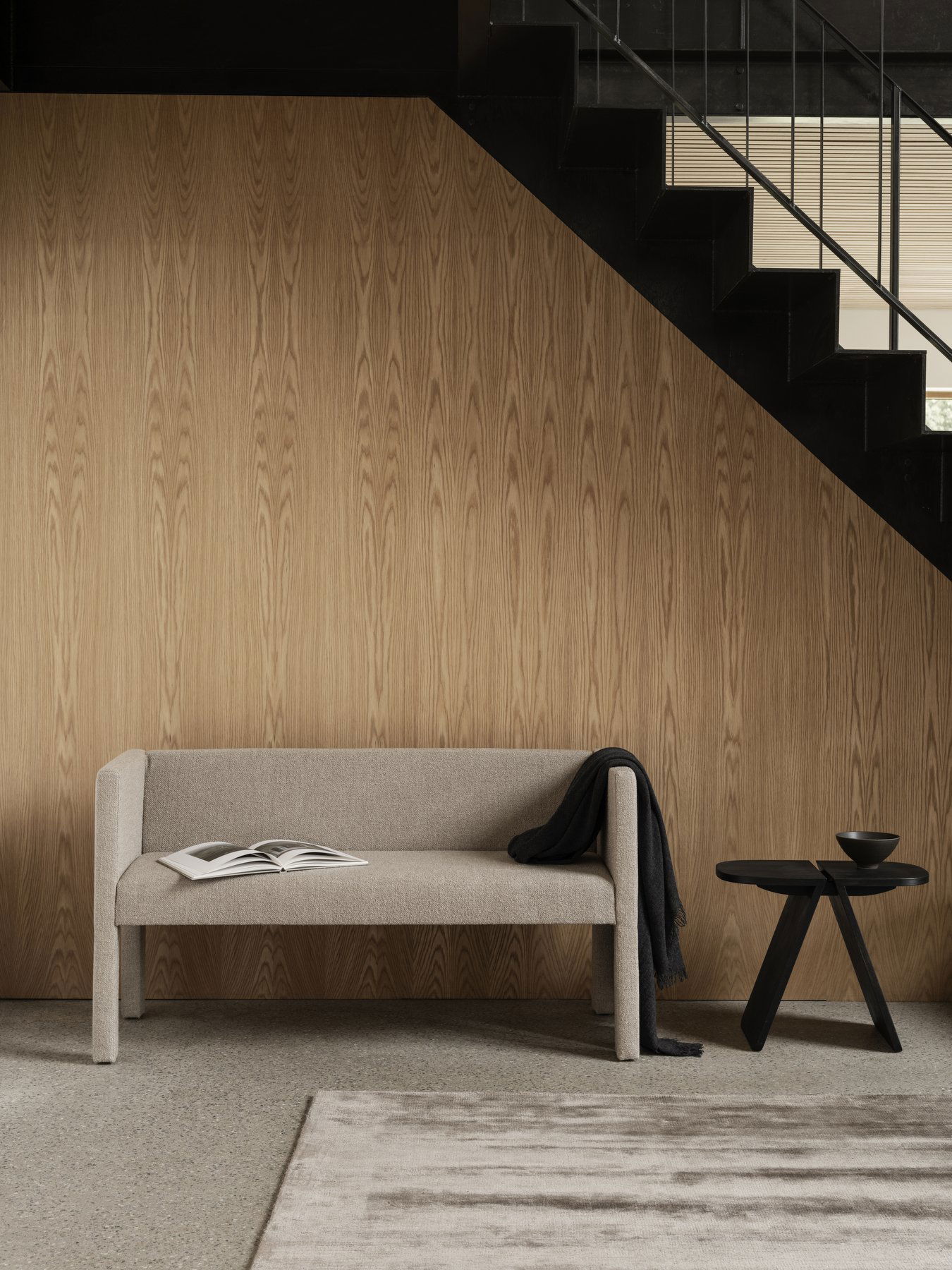 Gemütlicher Wohnraum mit einem minimalistischen Sofa und einem modernen Beistelltisch vor einer Holzwand.