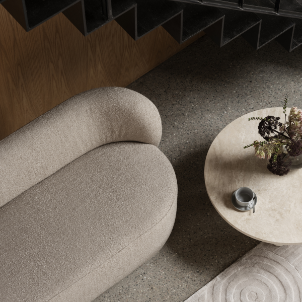 Elegantes Wohnzimmer mit einem gebogenen beigen Sofa und einem runden Marmortisch.
