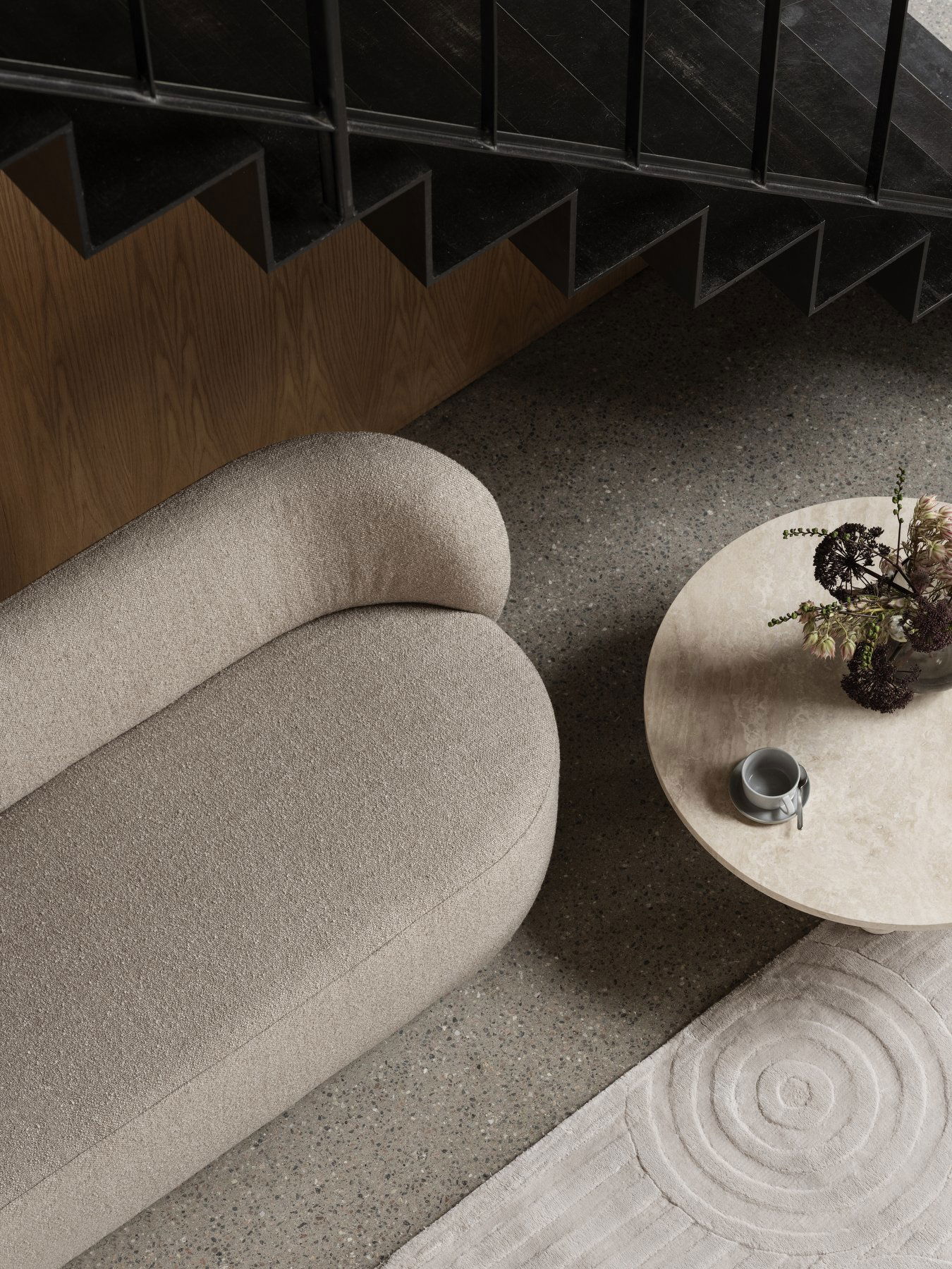 Elegantes Wohnzimmer mit einem gebogenen beigen Sofa und einem runden Marmortisch.