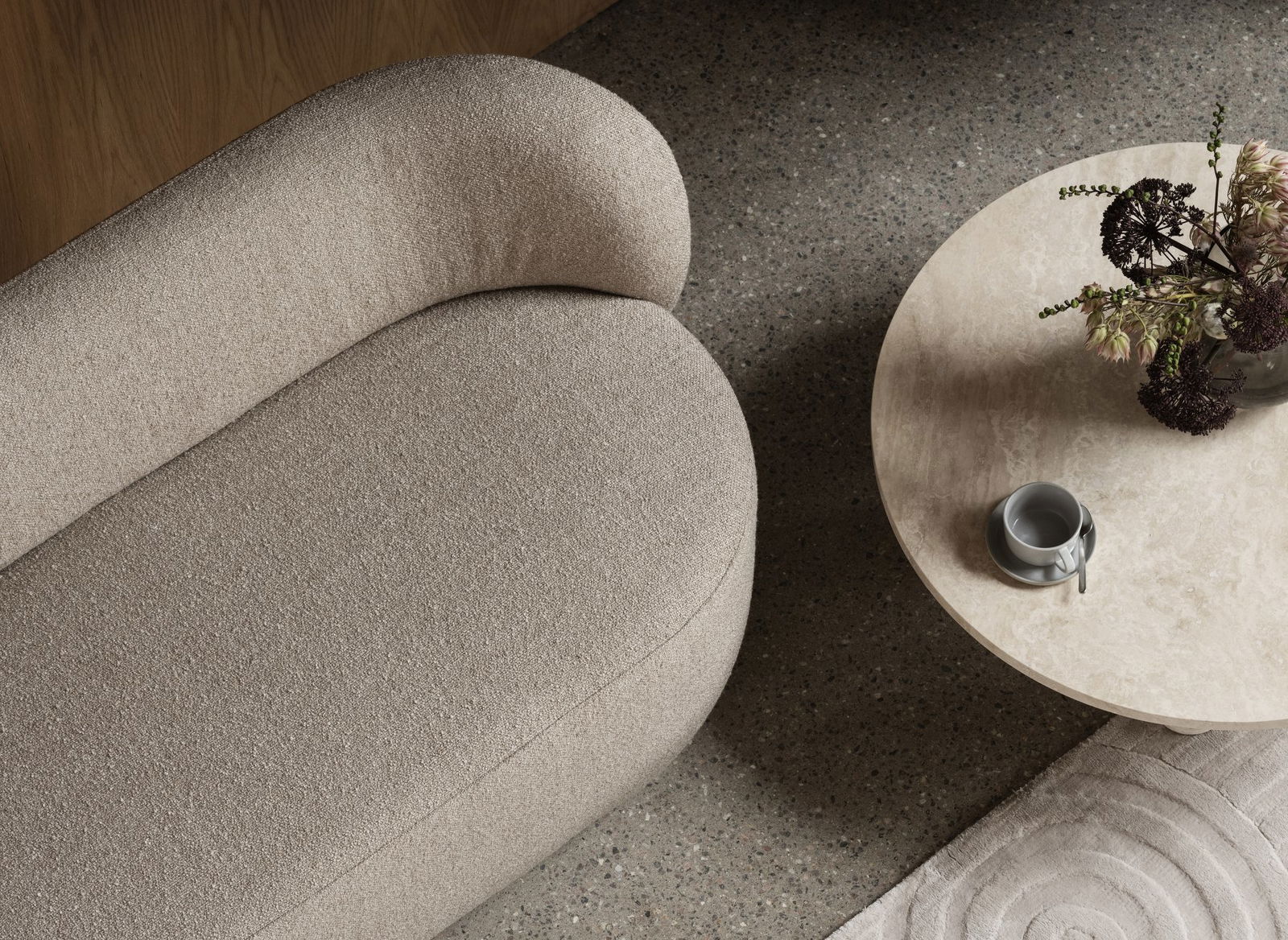 Elegantes beiges Sofa neben einem runden Couchtisch mit Blumen und einer Tasse platziert.