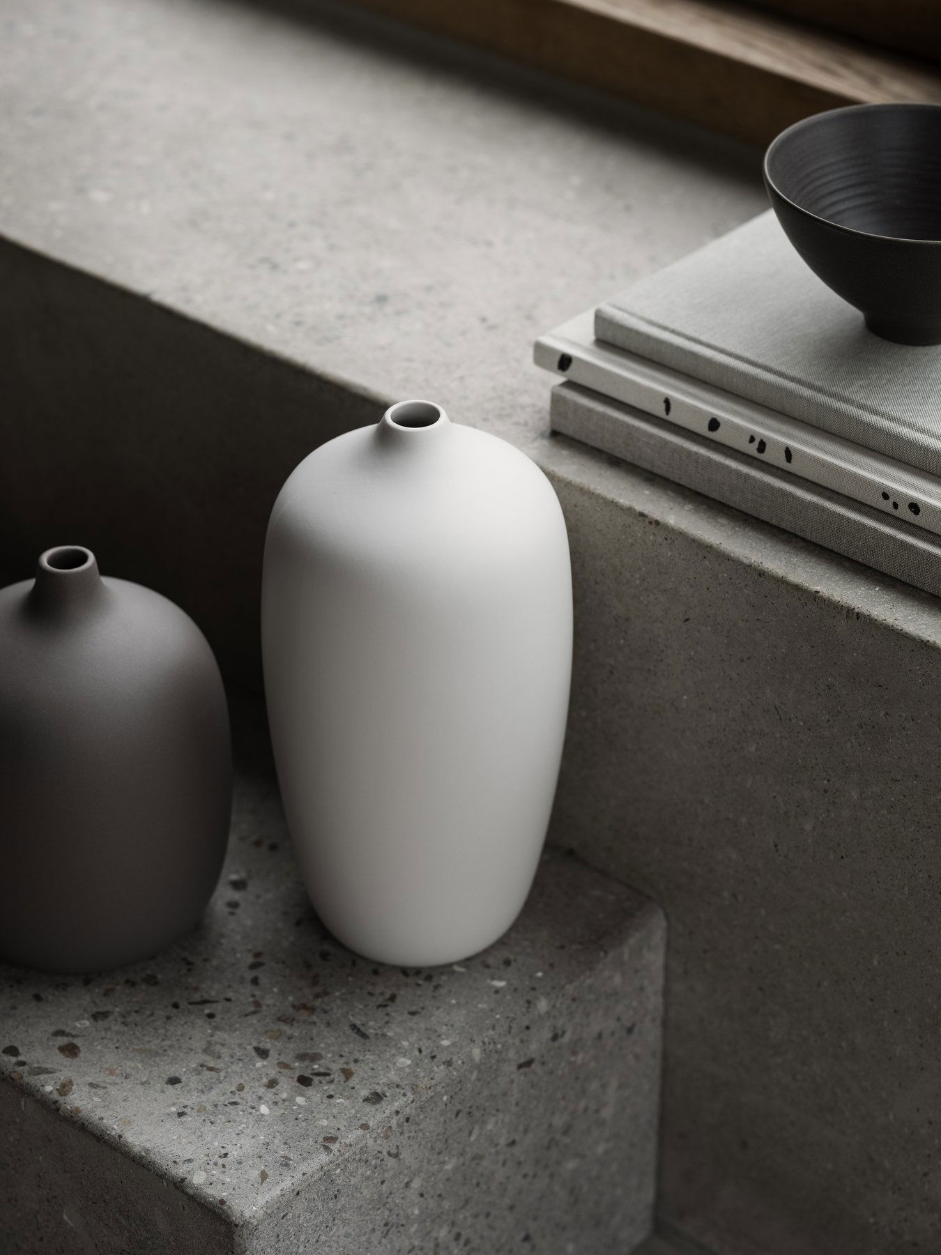 Minimalistische Keramikvasen in neutralen Tönen auf einer strukturierten Oberfläche, die moderne Dekoration betonen.