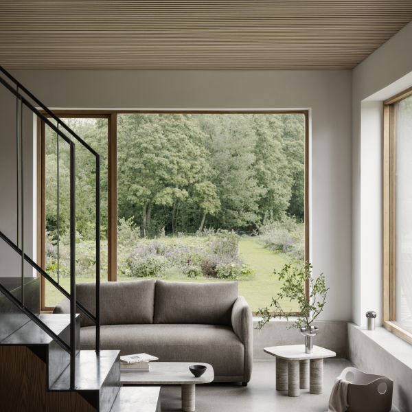 Moderner Wohnraum mit einem gemütlichen Sofa und einem weiten Blick auf einen üppigen Garten draußen.