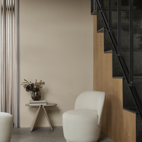 Minimalist interior with modern seating and decorative flowers by staircase.