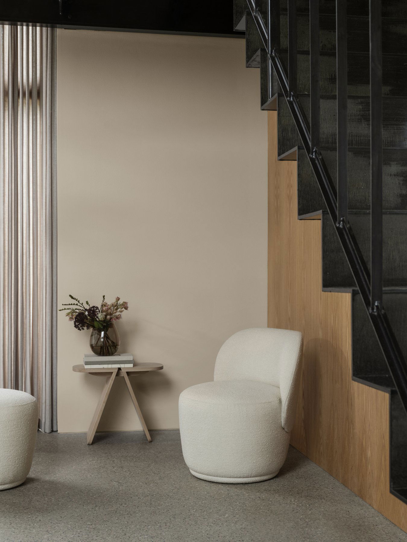 Minimalist interior with modern seating and decorative flowers by staircase.