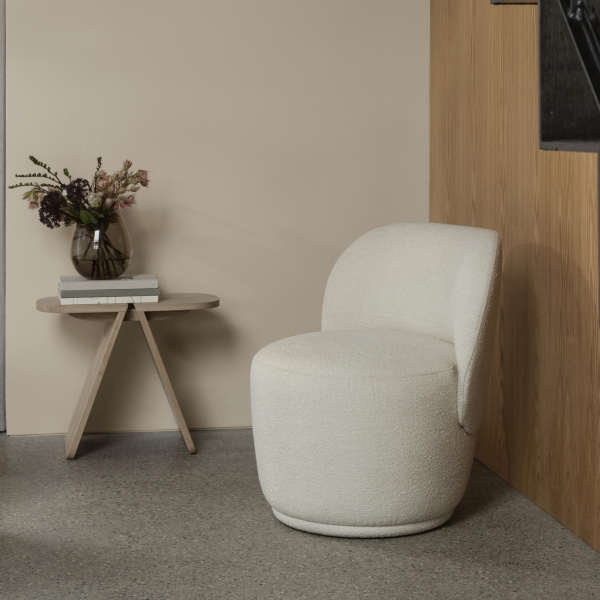 Cozy modern chair and minimalist side table against a neutral backdrop.