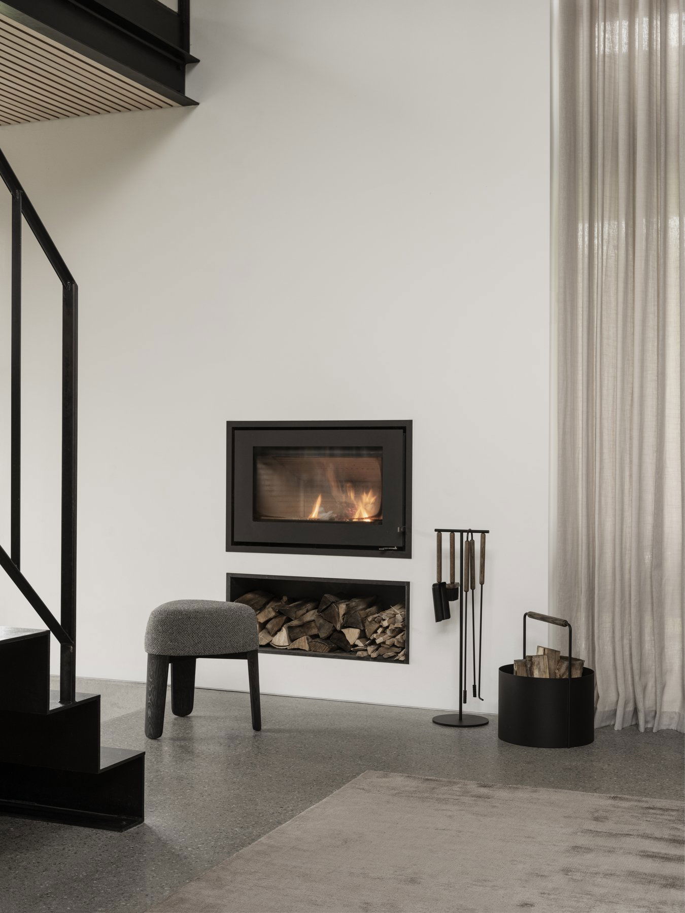 Modern living room with a sleek fireplace, wood storage, and stylish furniture.