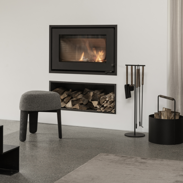 Modern living room with a black wall fireplace, log storage, and stylish seating.