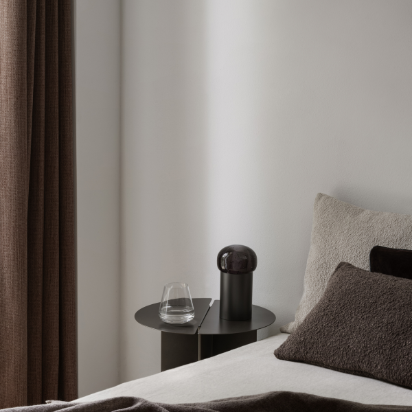 Modernes Schlafzimmerinterieur mit einem minimalistischen Nachttisch, Glas und dekorativer Lampe.