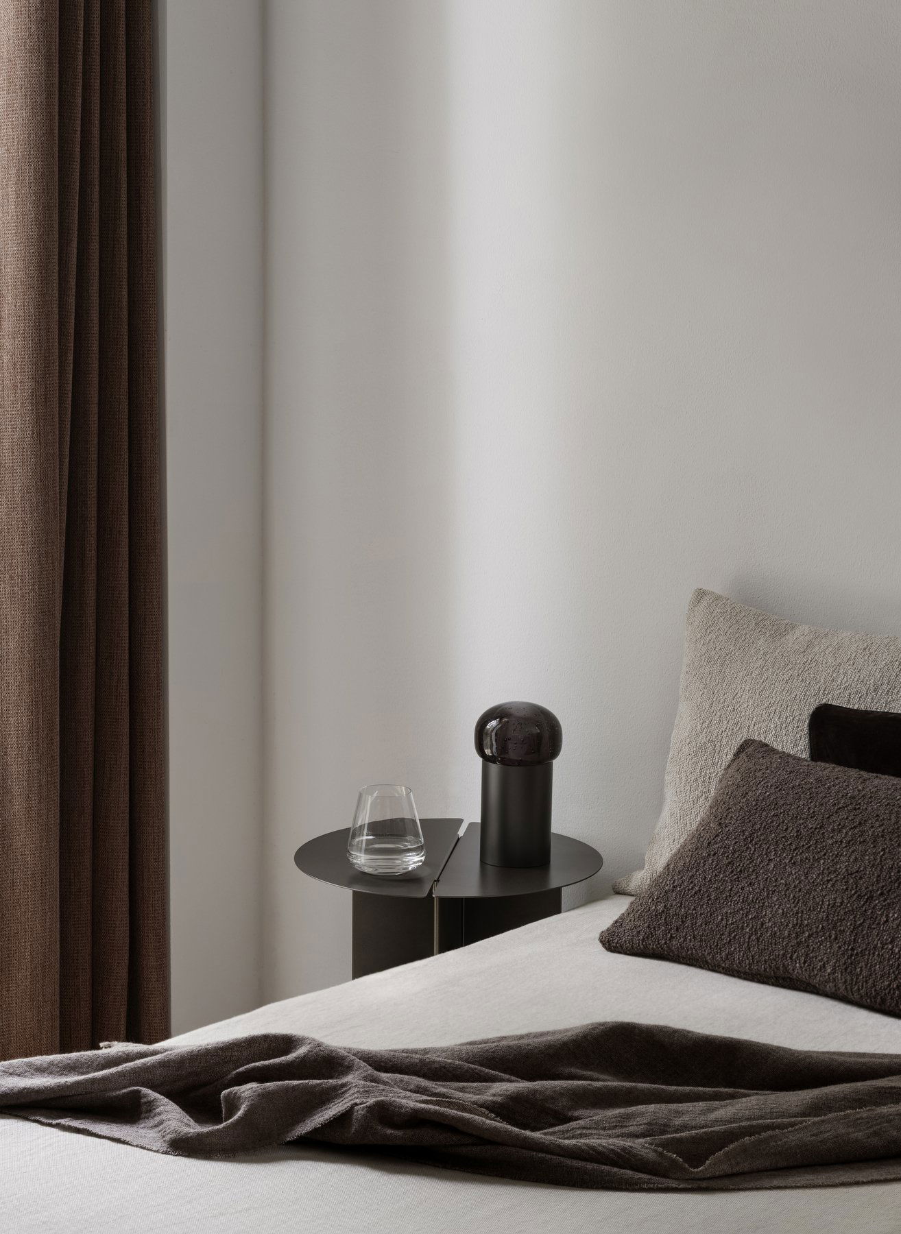 Modernes Schlafzimmerinterieur mit einem minimalistischen Nachttisch, Glas und dekorativer Lampe.
