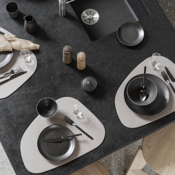 Elegant modern dining setup with black tableware on a sleek dark countertop.