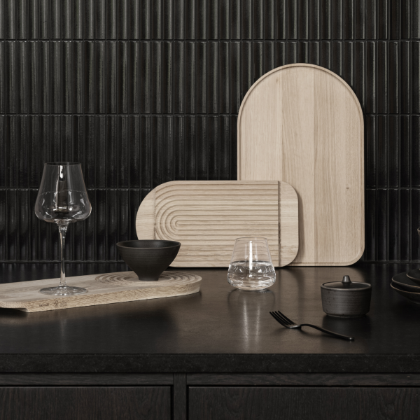Elegante Holzservierplatten und Glaswaren auf einer dunklen Küchenarbeitsplatte.