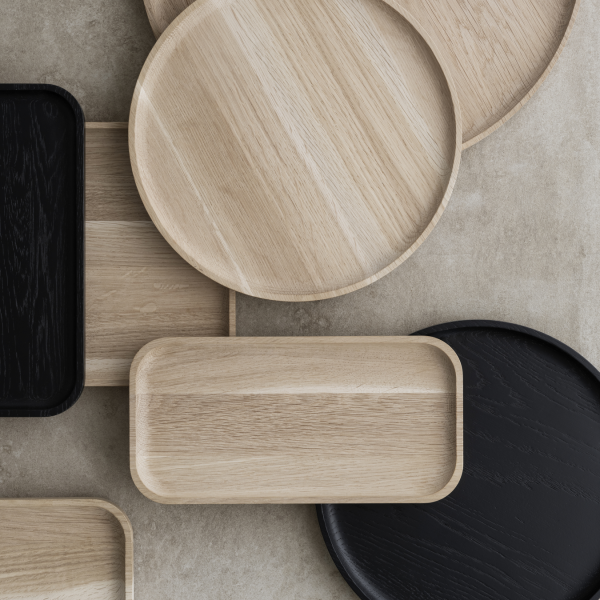 Stylish wooden serving trays in various shapes and colors on a textured surface.