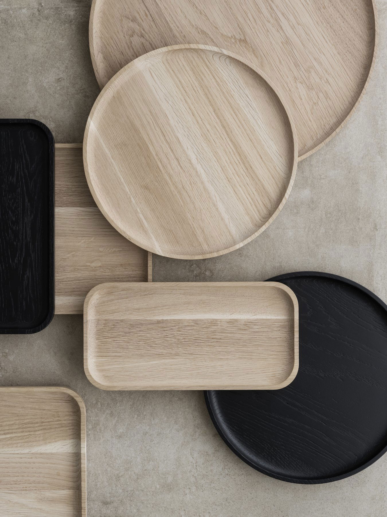 Stylish wooden serving trays in various shapes and colors on a textured surface.