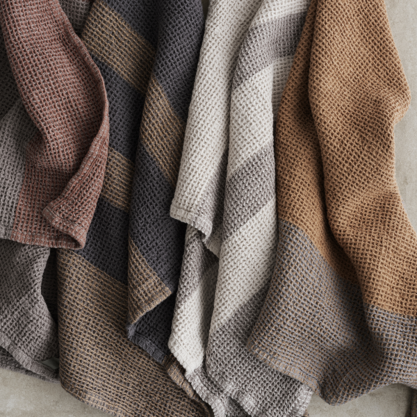 Cozy textured blankets in warm, earthy tones draped elegantly on a neutral surface.