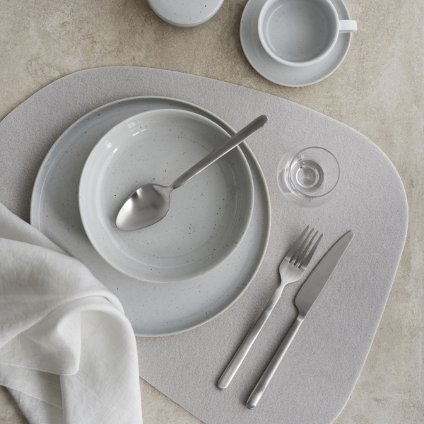 Elegant dining setting with gray tableware, cutlery, and a linen napkin on a neutral surface.