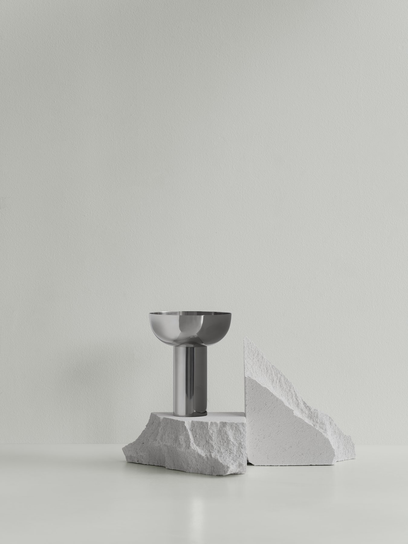 Stylische moderne Vase auf einem strukturierten Steindisplay vor einer minimalistischen hellgrünen Wand.