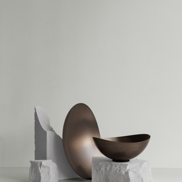 Moderne Bronze-Schalen, die auf strukturierten Betonblöcken vor einem sanften Pastellhintergrund präsentiert werden.