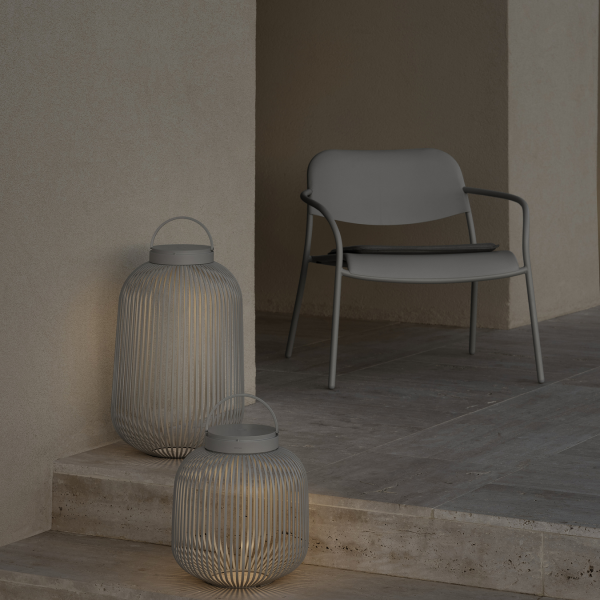 Stilvolle Außendekoration mit modernen Laternen und einem minimalistischen Stuhl auf einer Terrasse.