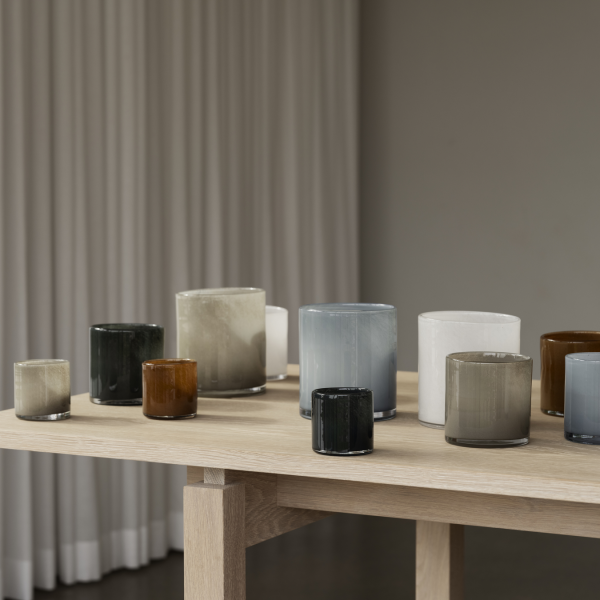 Stylish glass candle holders in various shapes and colors on a wooden table.