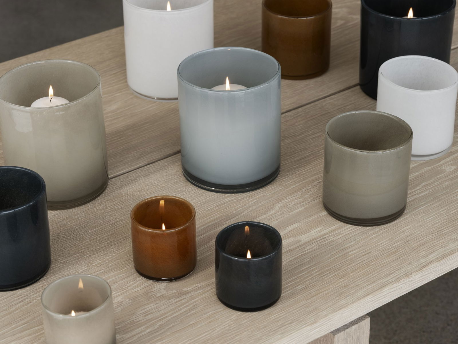 A variety of stylish scented candles in glass containers on a wooden table.