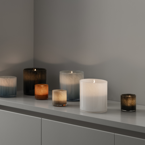 Elegant collection of candle holders in varying colors and sizes on a sleek surface.