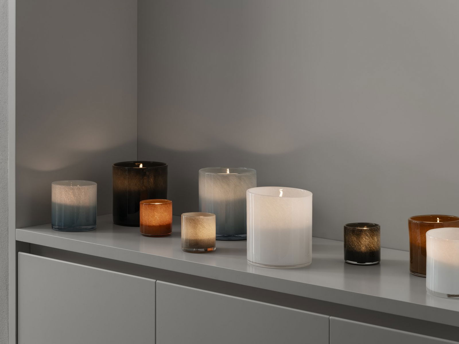 Elegant collection of candle holders in varying colors and sizes on a sleek surface.