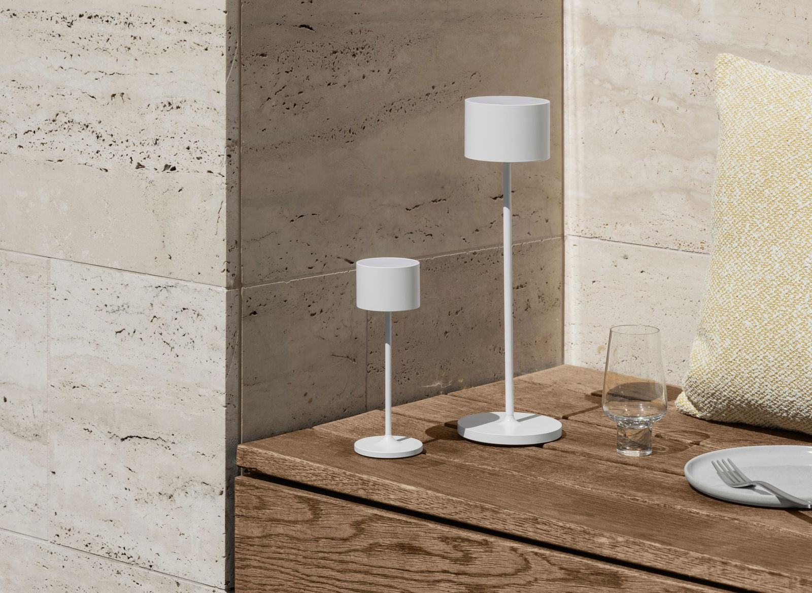 Zwei moderne weiße Tischlampen auf einer Holzoberfläche mit einem dekorativen Glas in einem eleganten Raum.