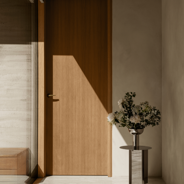 Modernes Interieur mit einer Holztür und einer minimalistischen Vase mit Blumen.