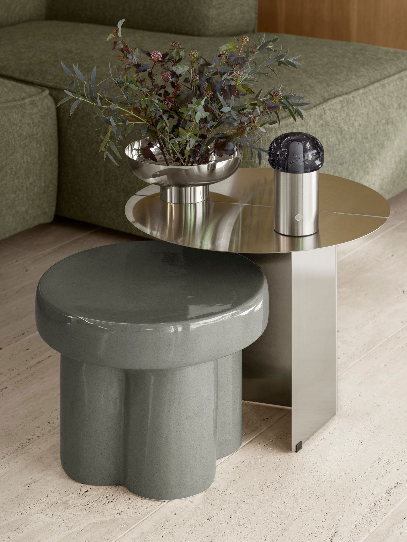 Zeitgenössischer Wohnraum mit einem metallischen Beistelltisch und einem eleganten Hocker mit einer Vase.