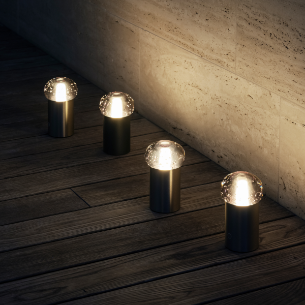 Moderne Außenbeleuchtung mit Glasdomeformen, die die Holzterrasse bei Nacht beleuchten.
